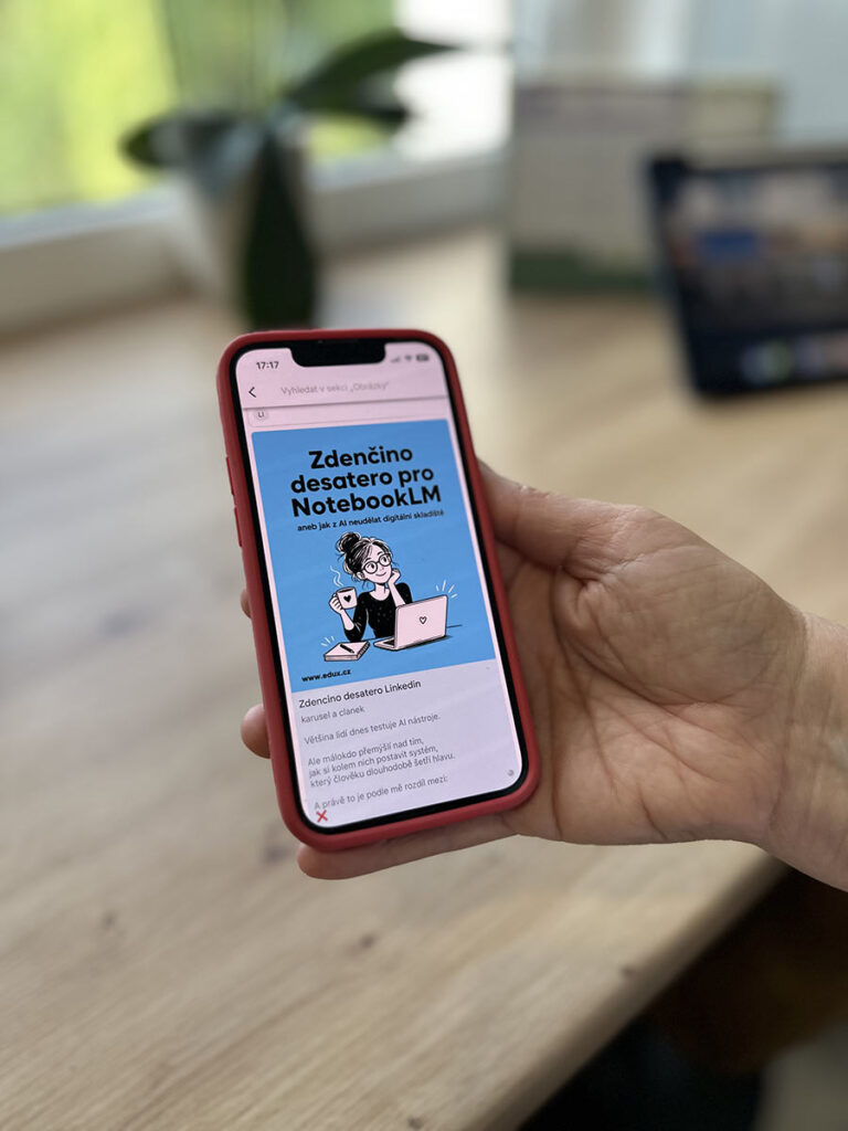 Mobilní telefon na dřevěném stole s kytkou v Google Keep a ilustrací karikatury Zdenky Tomaidesové s textem Zdenčino desatero v NotebookLM – EDUX.cz.